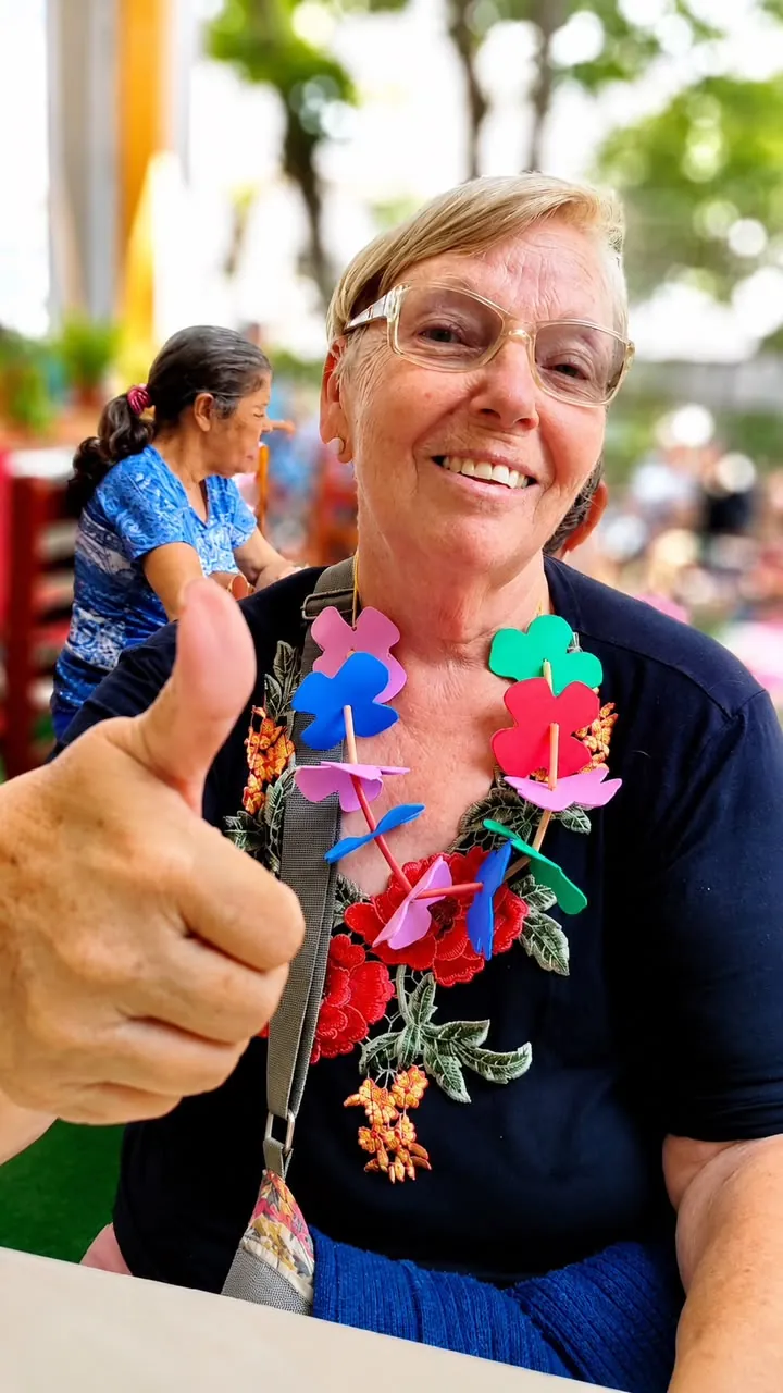 Moradora sorrindo com colar de flores durante uma atividade no residencial