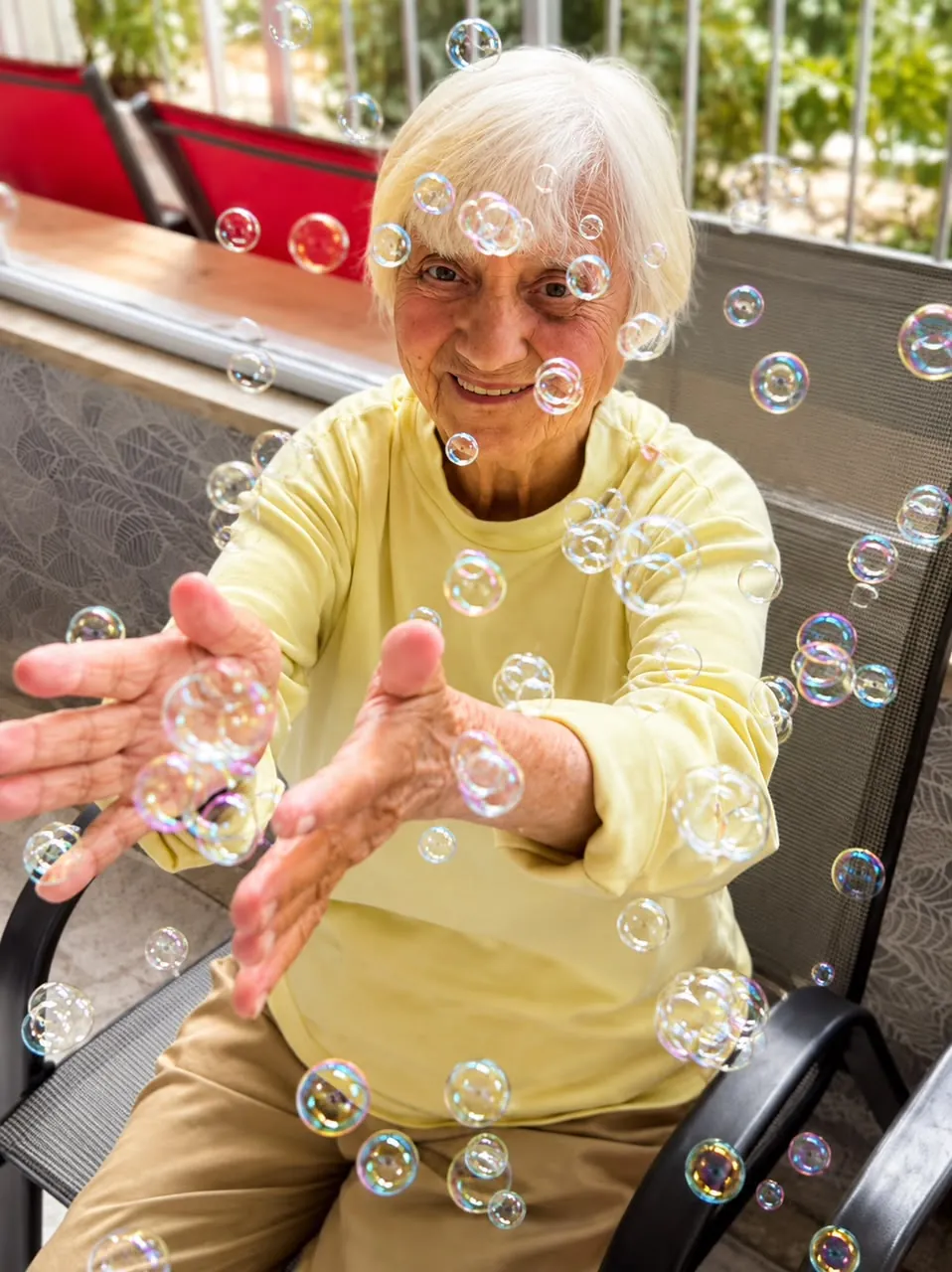 Moradora sorrindo brincando com bolhas de sabão no residencial